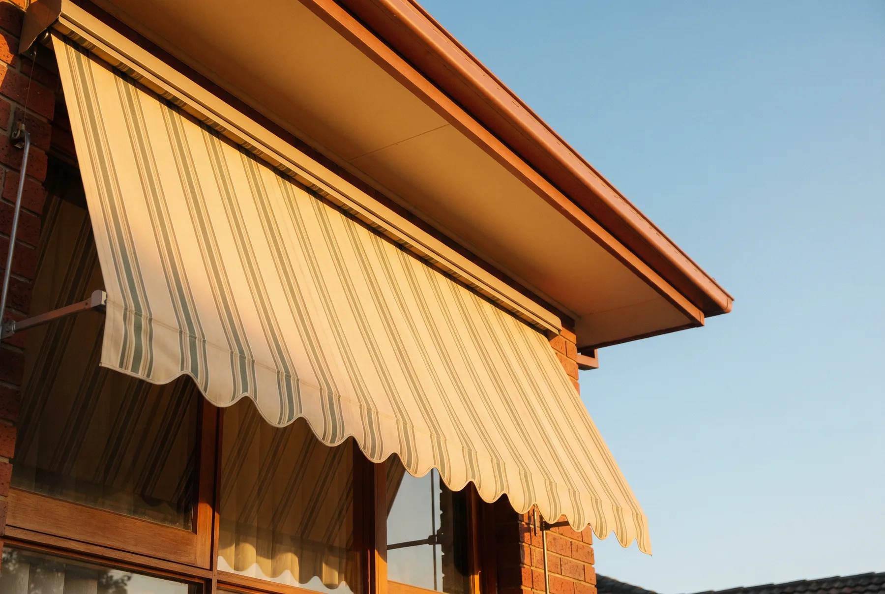 A canvas window awning casting shade, seen from below against afternoon sky