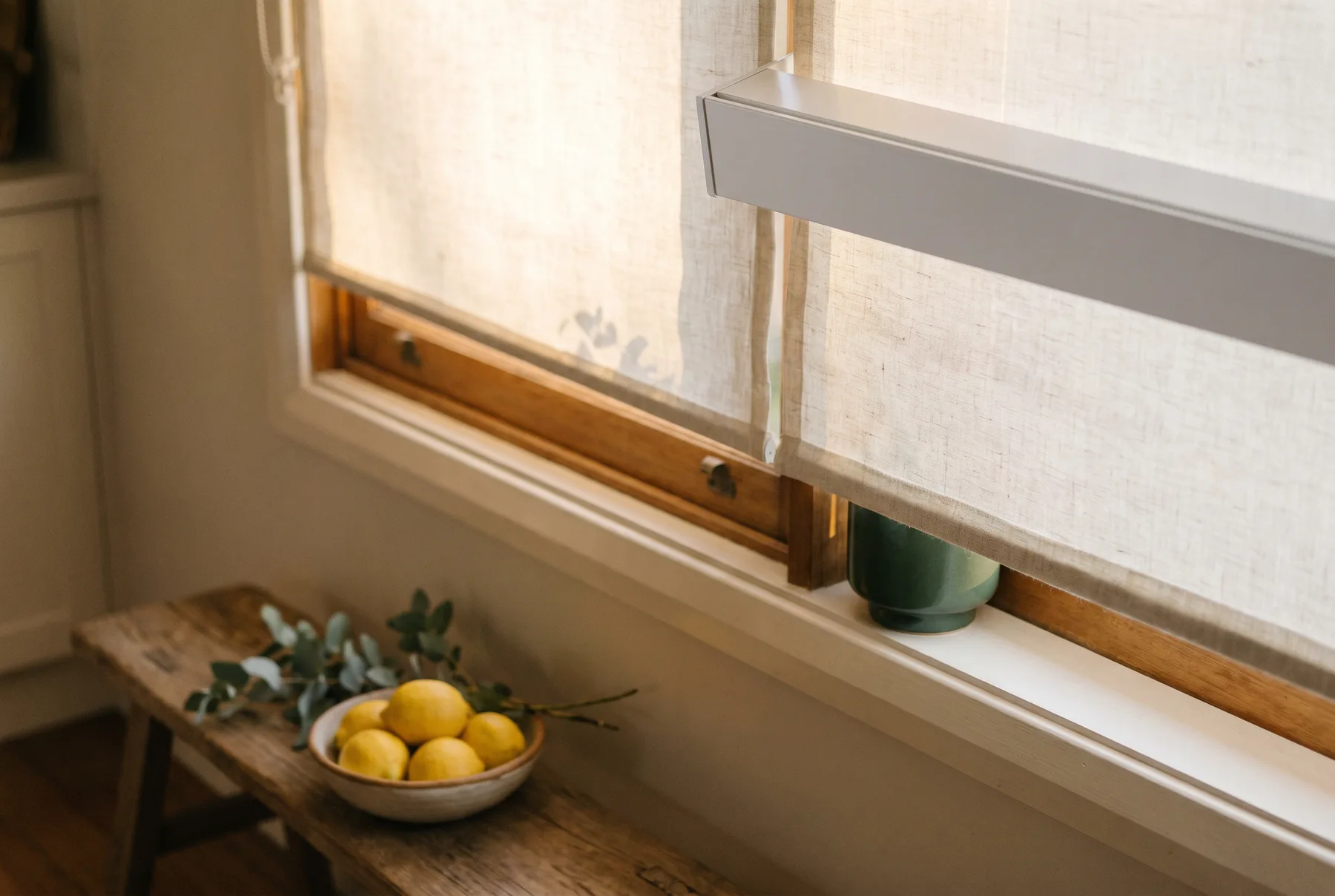 A roller blind half lowered over a bright kitchen window